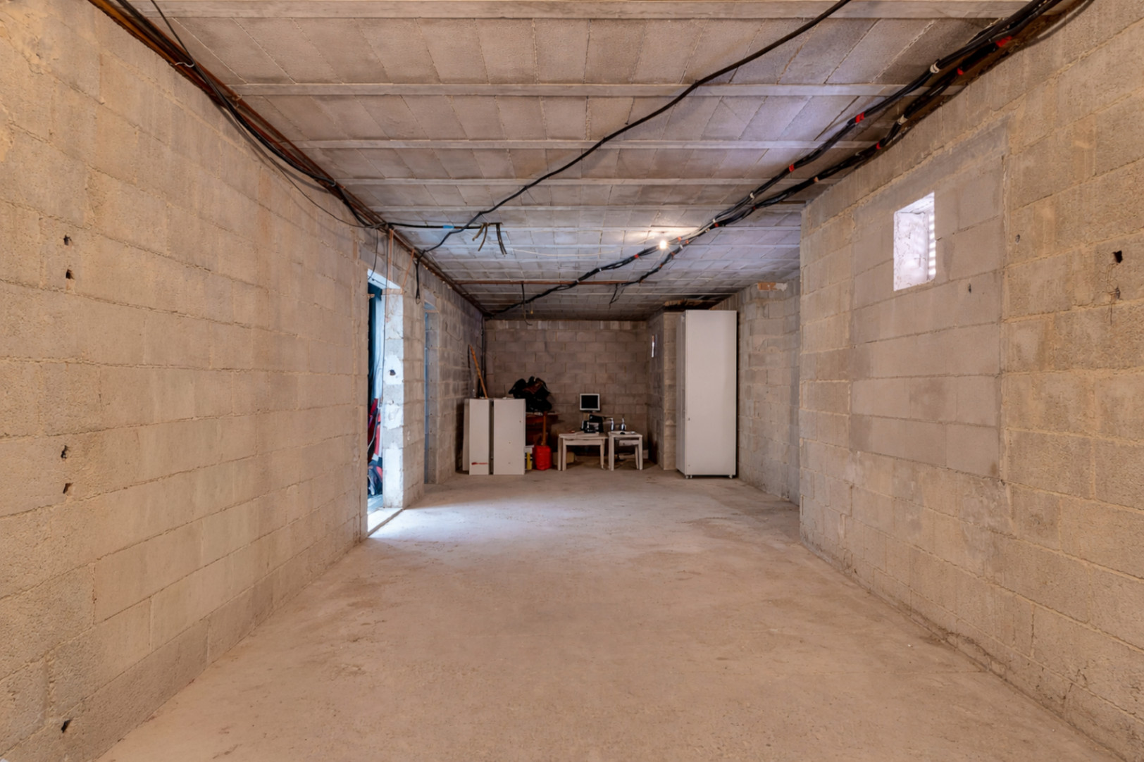 Vaste espace brut avec murs en parpaings et plafonds hauts, offrant un grand potentiel d'aménagement pour des chambres supplémentaires ou un appartement indépendant.