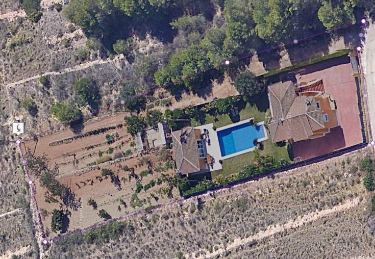 Vue aérienne de la parcelle délimitée comprenant la villa principale, la piscine de 15x6 m, le bâtiment barbecue et une vaste zone agricole plate.