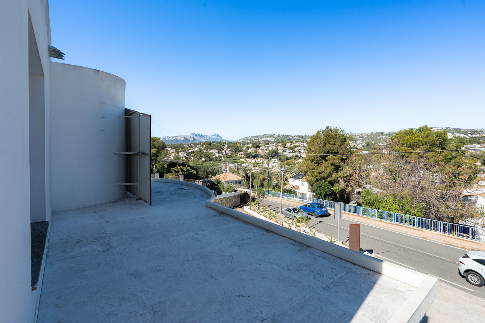 Grande terrasse avec carrelage clair offrant une vue panoramique sur la Sierra de Bernia et les environs résidentiels.