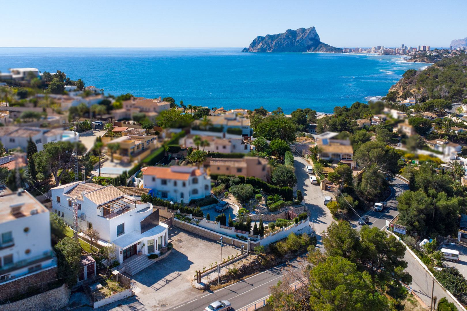 Vue aérienne du bâtiment situé le long de la route côtière, offrant un panorama sur la mer Méditerranée et le célèbre rocher Peñón de Ifach.