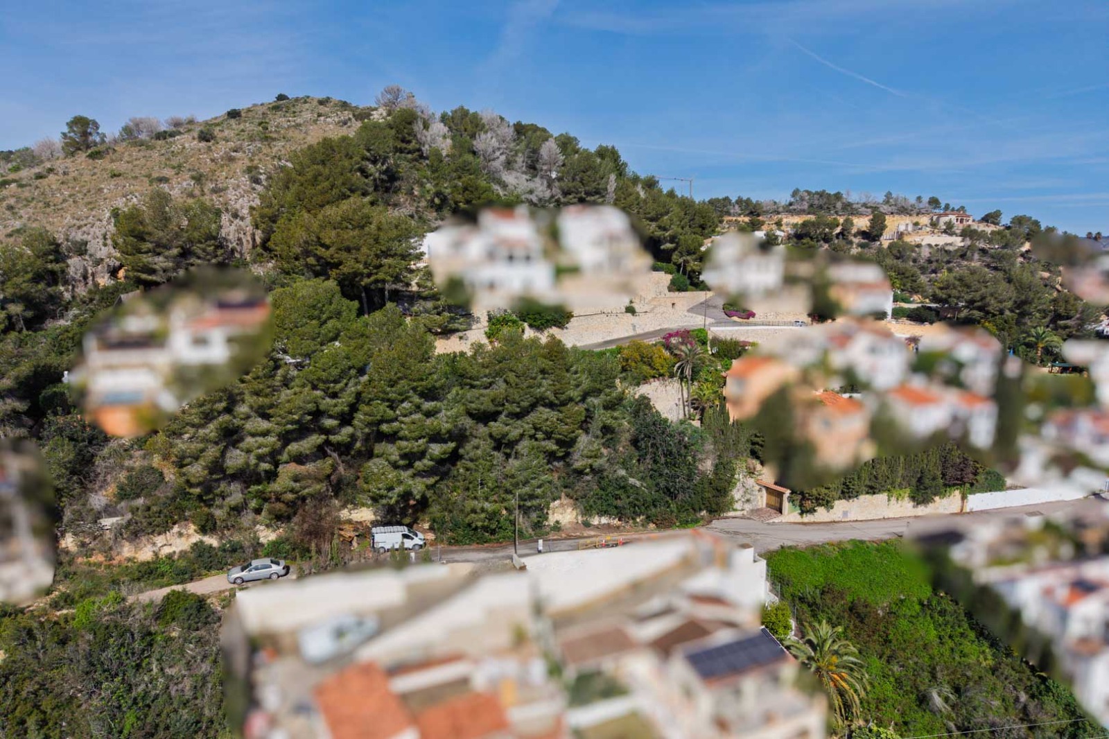 Vue aérienne de la colline boisée à Sol de Este, illustrant l'intégration de villas méditerranéennes parmi les pins et les routes d'accès goudronnées.