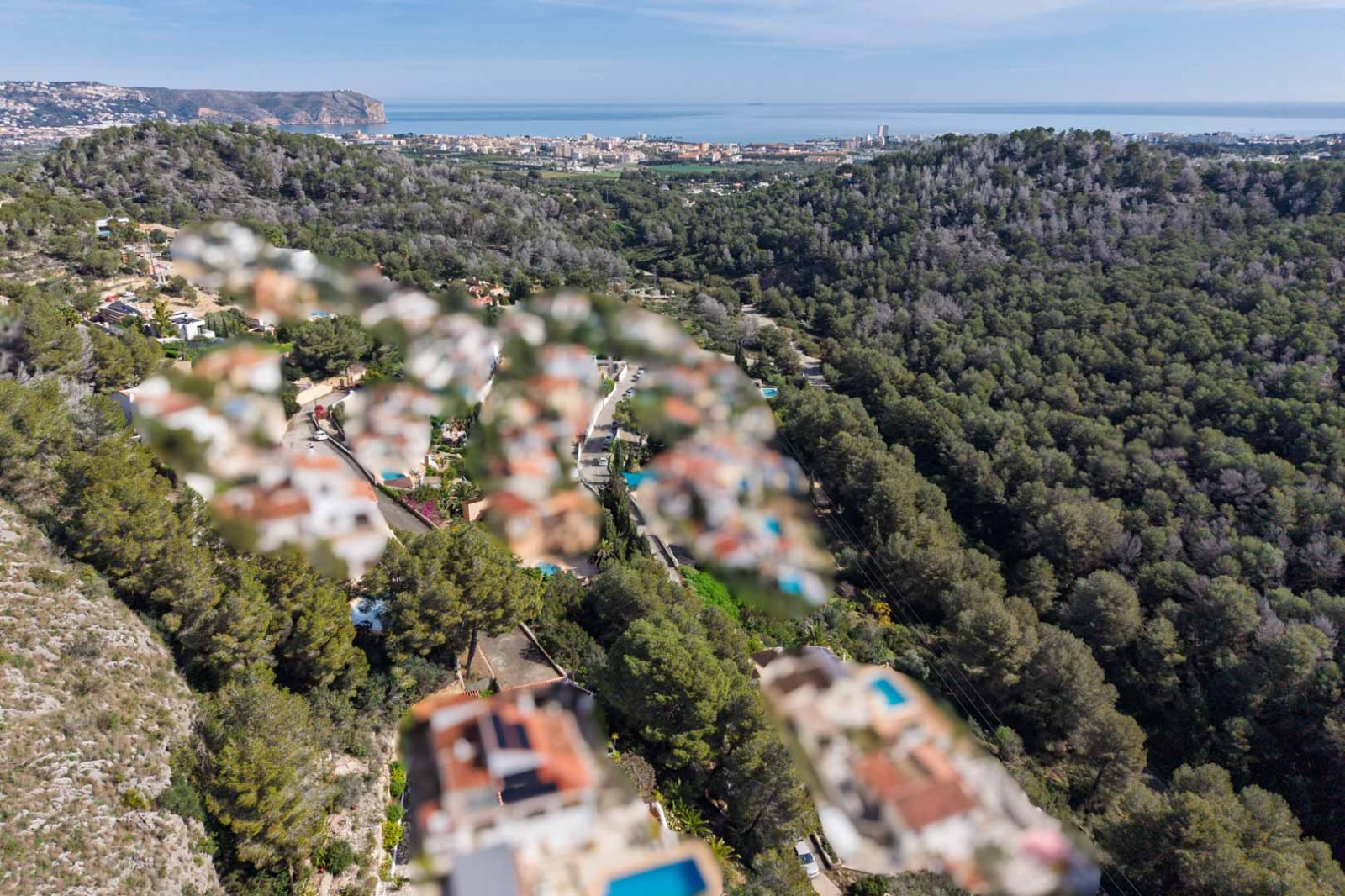 Vue aérienne panoramique depuis Sol de Este, surplombant des collines boisées avec une perspective dégagée sur la côte de Jávea et la mer.