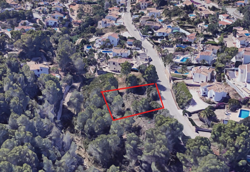 Vue aérienne du terrain de 826 m2 délimité en rouge, situé dans un quartier résidentiel boisé avec un accès direct par une route goudronnée.