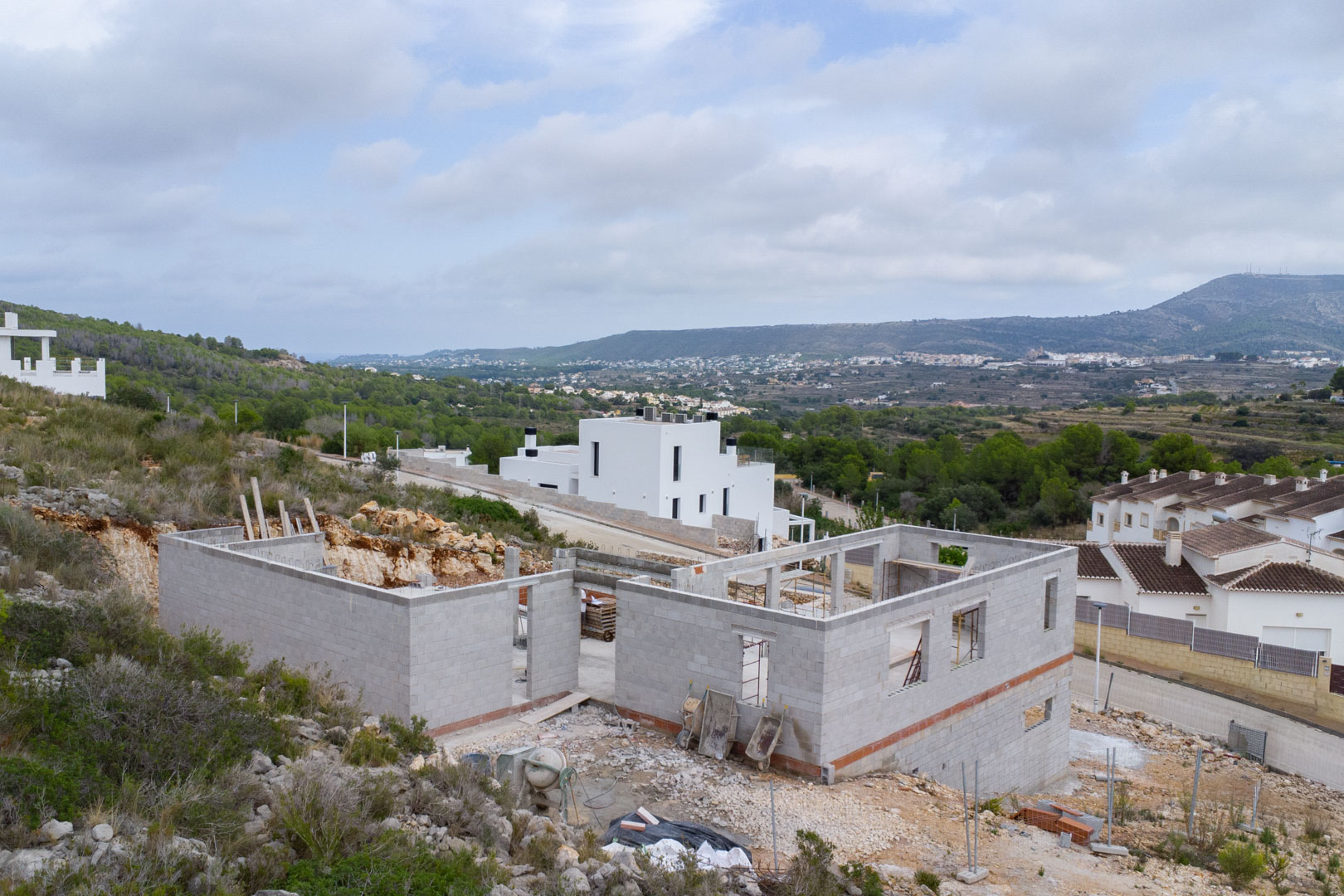 Phase de construction d'une villa moderne à Pedreguer, illustrant la structure en parpaings et les vues panoramiques sur la vallée et les montagnes.