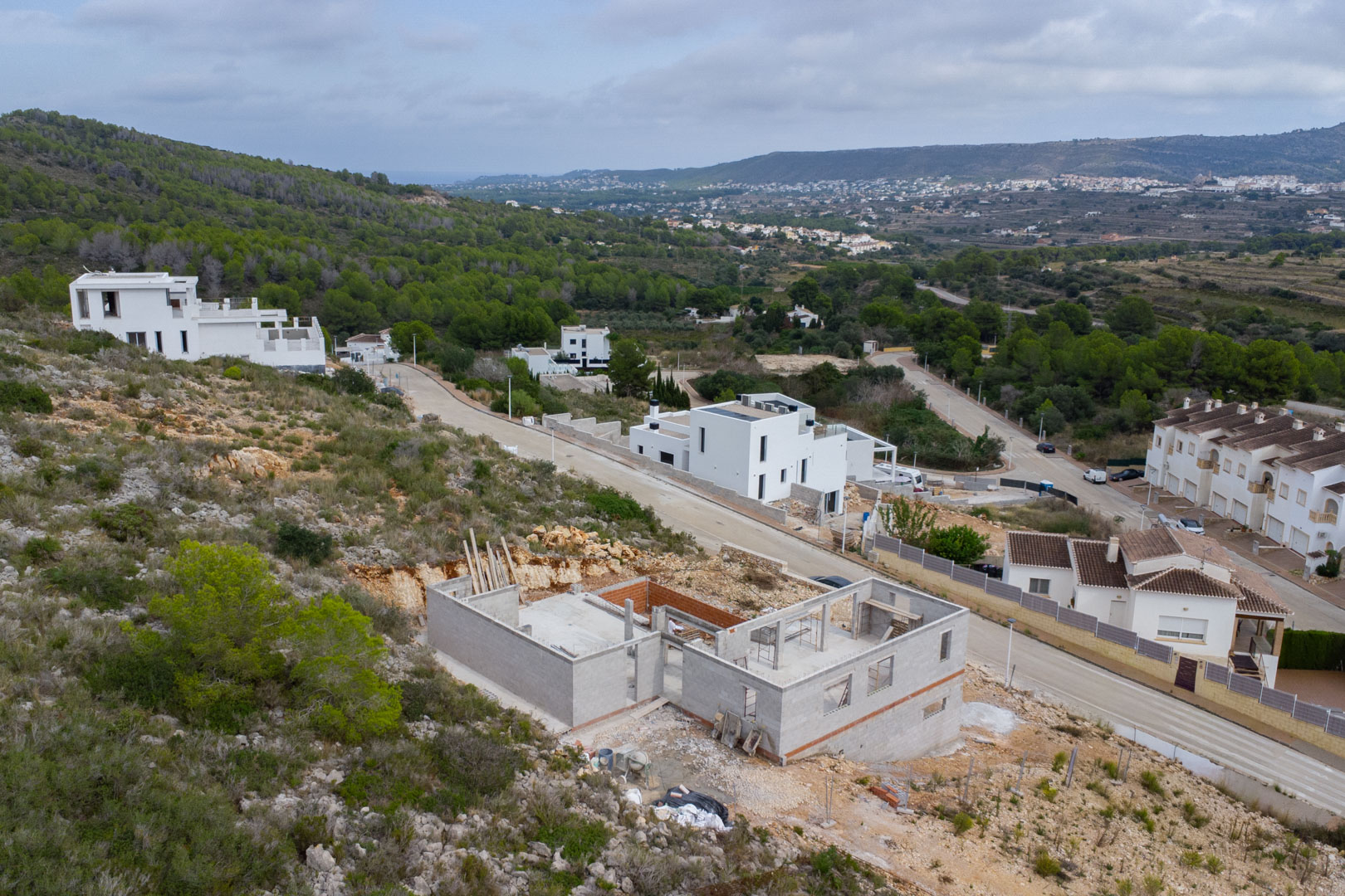 Vue aérienne de la villa en construction à Pedreguer, montrant la structure en béton et les fondations sur un terrain en pente avec vue sur la vallée.