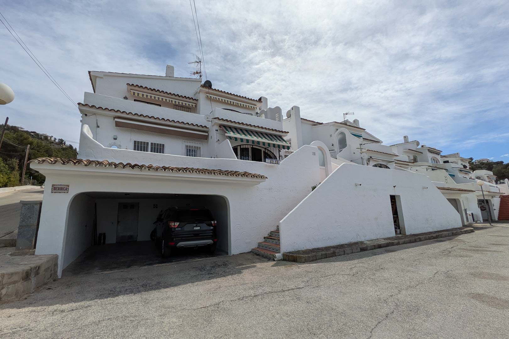 Façade extérieure avec garage privé au niveau de la rue et escaliers ornés de carreaux traditionnels menant aux niveaux supérieurs de la résidence.