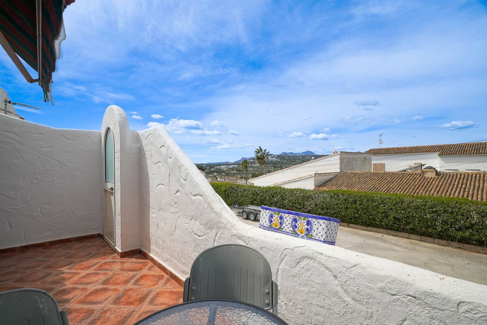 Terrasse surélevée avec sol en grès rustique offrant une vue dégagée sur la vallée. Elle dispose d'un rangement extérieur intégré dans les murs en maçonnerie blanche.