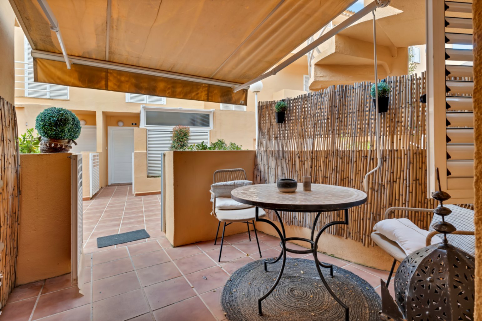 Terrasse privée avec auvent, carrelage rougeâtre et mobilier d'extérieur aux détails bohèmes.