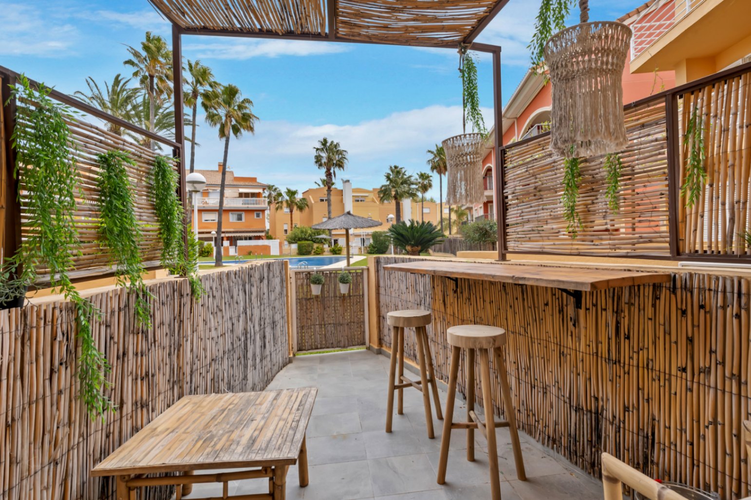Terrasse privée avec bar en bambou, donnant sur la piscine commune et les jardins.