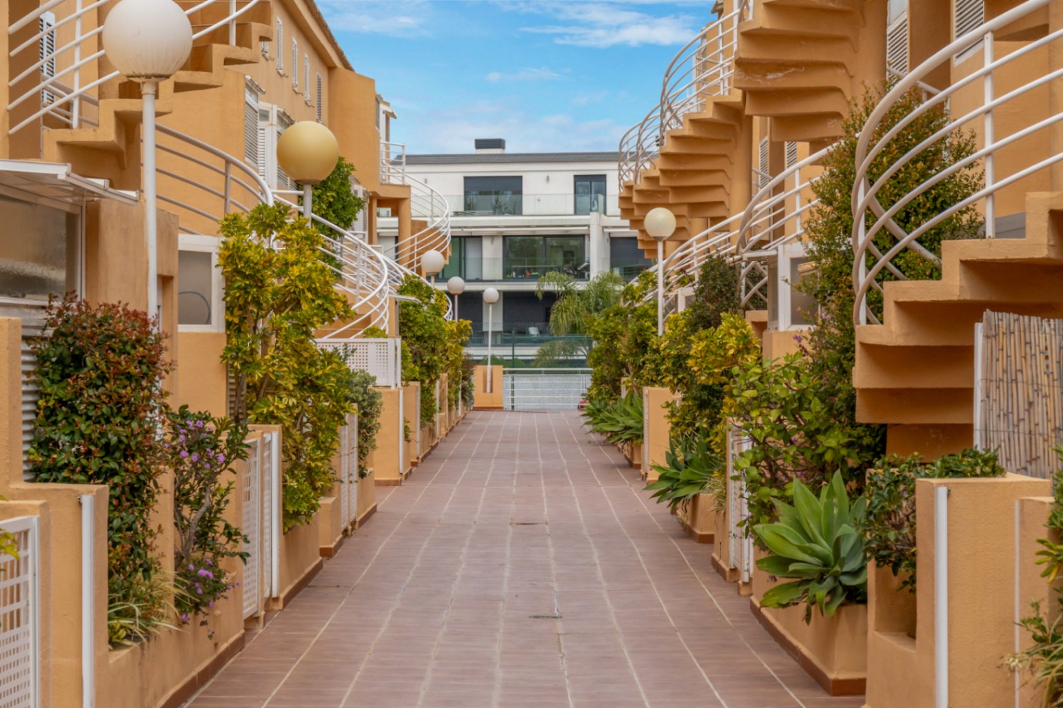 Vue du passage extérieur avec escaliers en colimaçon et jardinières.