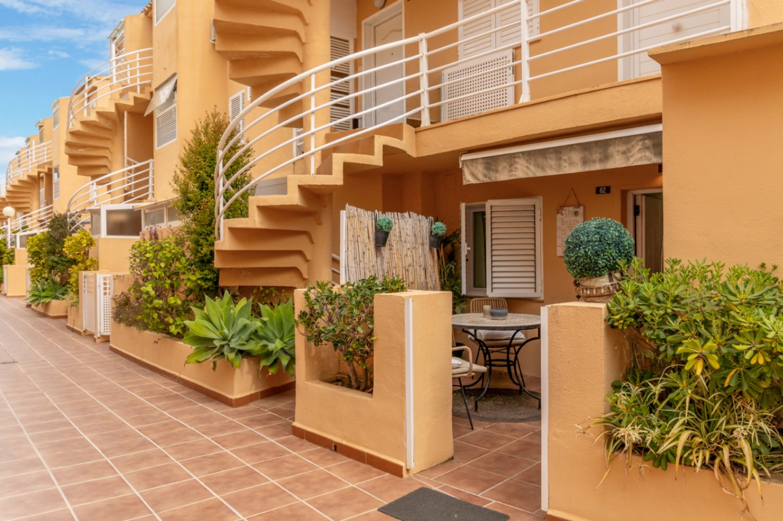 Vue extérieure de la terrasse privée avec table de bistro et accès à l'escalier en colimaçon.