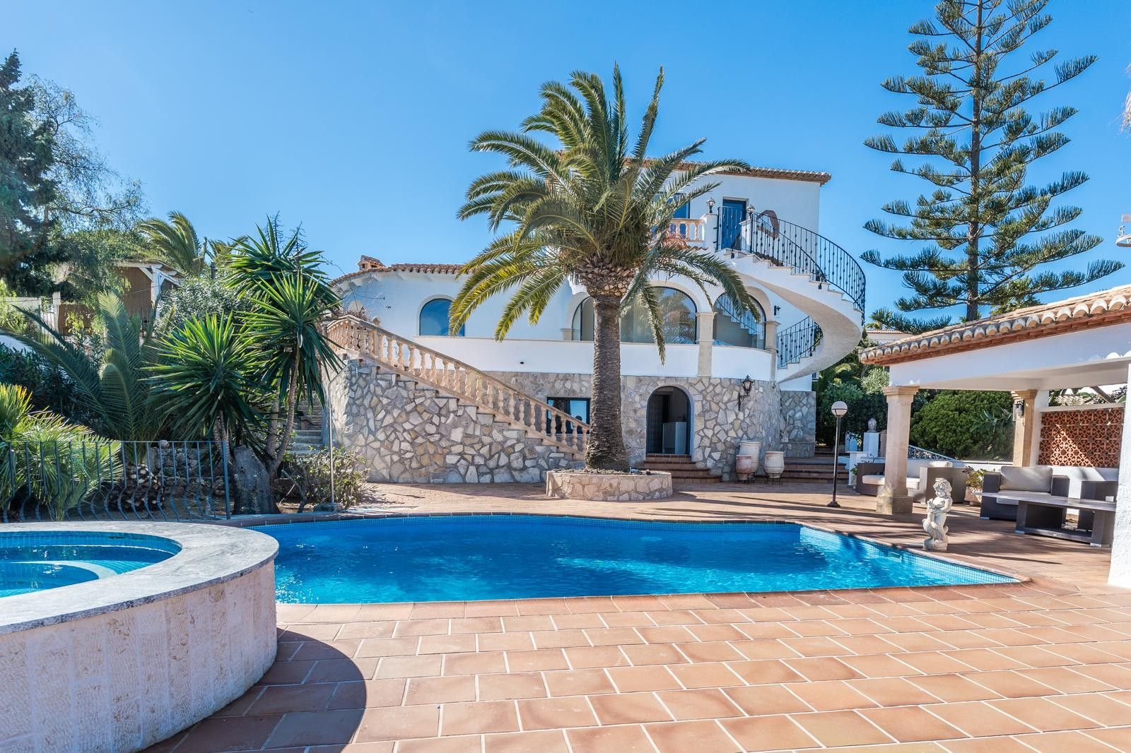 Extérieur de la villa avec piscine, jacuzzi circulaire et façade en pierre naturelle. Comprend un escalier en colimaçon extérieur et un jardin méditerranéen.