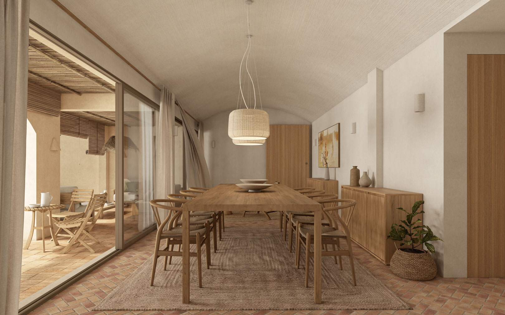Salle à manger avec plafond voûté, table en bois et chaises Wishbone sur sol en terre cuite. De larges baies vitrées s'ouvrent sur une terrasse couverte au style méditerranéen.