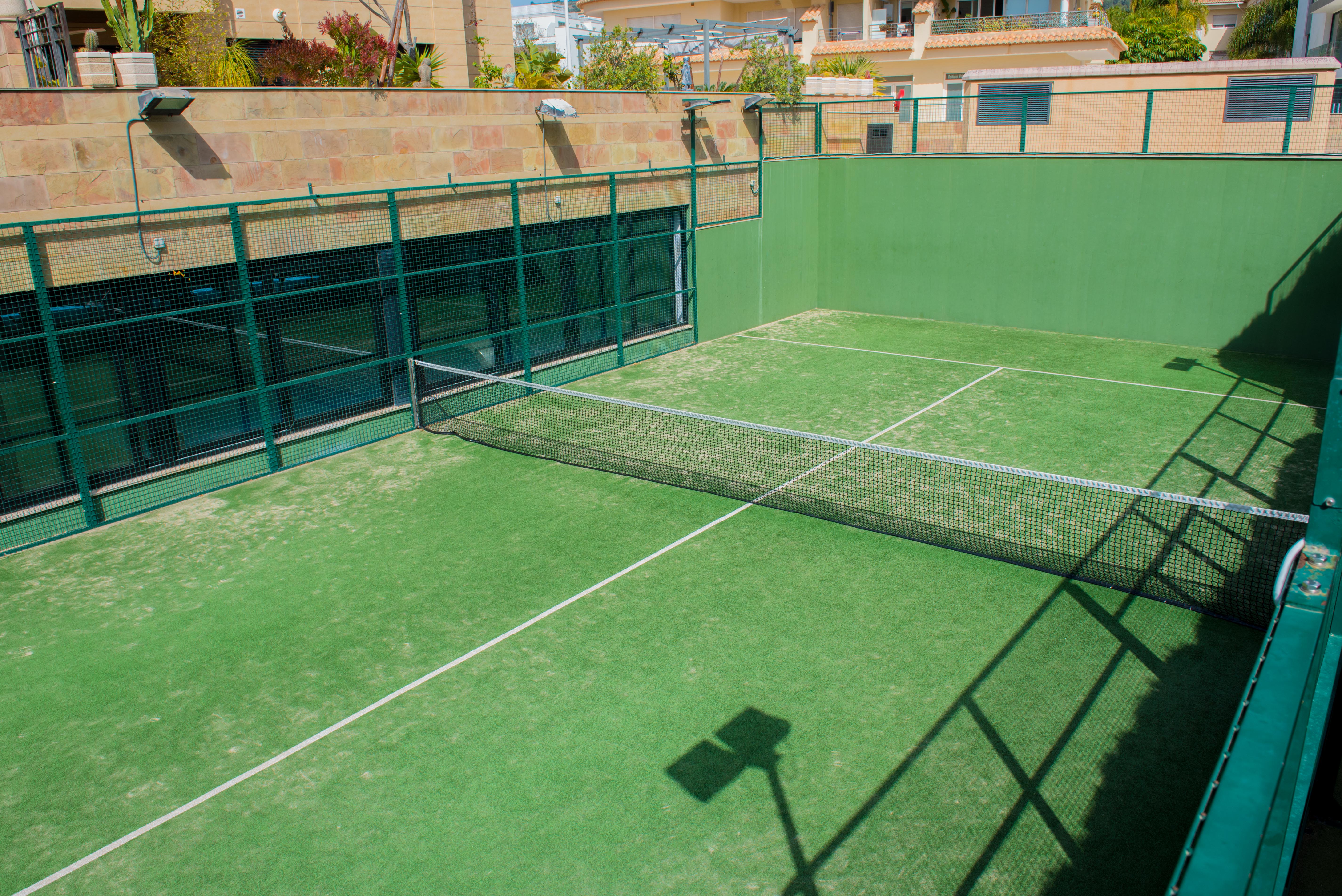 Court de padel privé avec gazon synthétique vert et clôture métallique, situé dans les espaces communs du complexe résidentiel à Jávea.