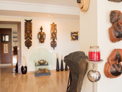 Un intérieur artistique présentant une collection soignée de masques et bustes en bois sculpté sur des murs clairs, complété par un parquet poli et des accents décoratifs modernes.