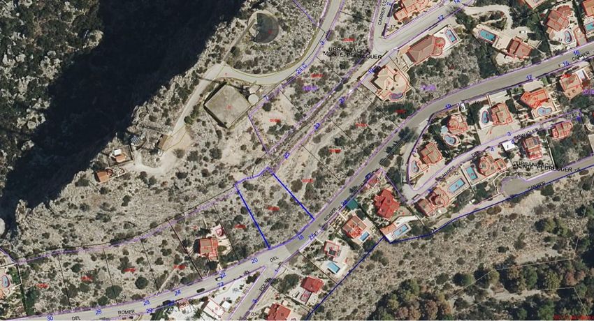 Vue aérienne de la parcelle urbaine, délimitée en bleu, située le long de la rue 'ROMER' dans l'urbanisation Monte Pedreguer. Le terrain non bâti est visible, entouré de propriétés résidentielles établies.