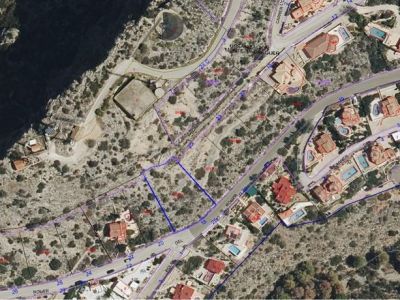 Vue aérienne de la parcelle urbaine, délimitée en bleu, située le long de la rue 'ROMER' dans l'urbanisation Monte Pedreguer. Le terrain non bâti est visible, entouré de propriétés résidentielles établies.