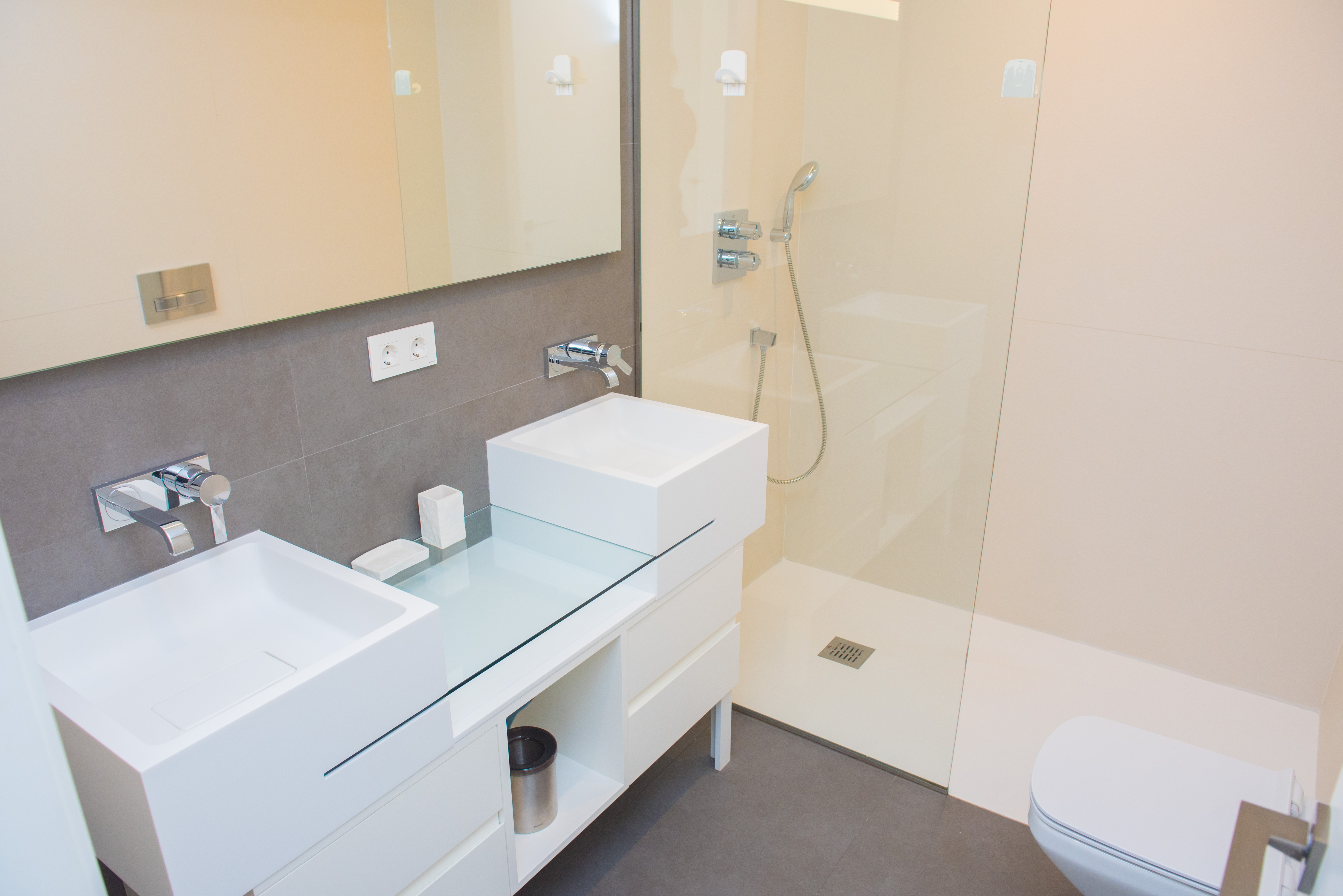 Salle de bain moderne avec double vasque au design minimaliste, robinetterie chromée encastrée et douche à l'italienne avec paroi en verre.