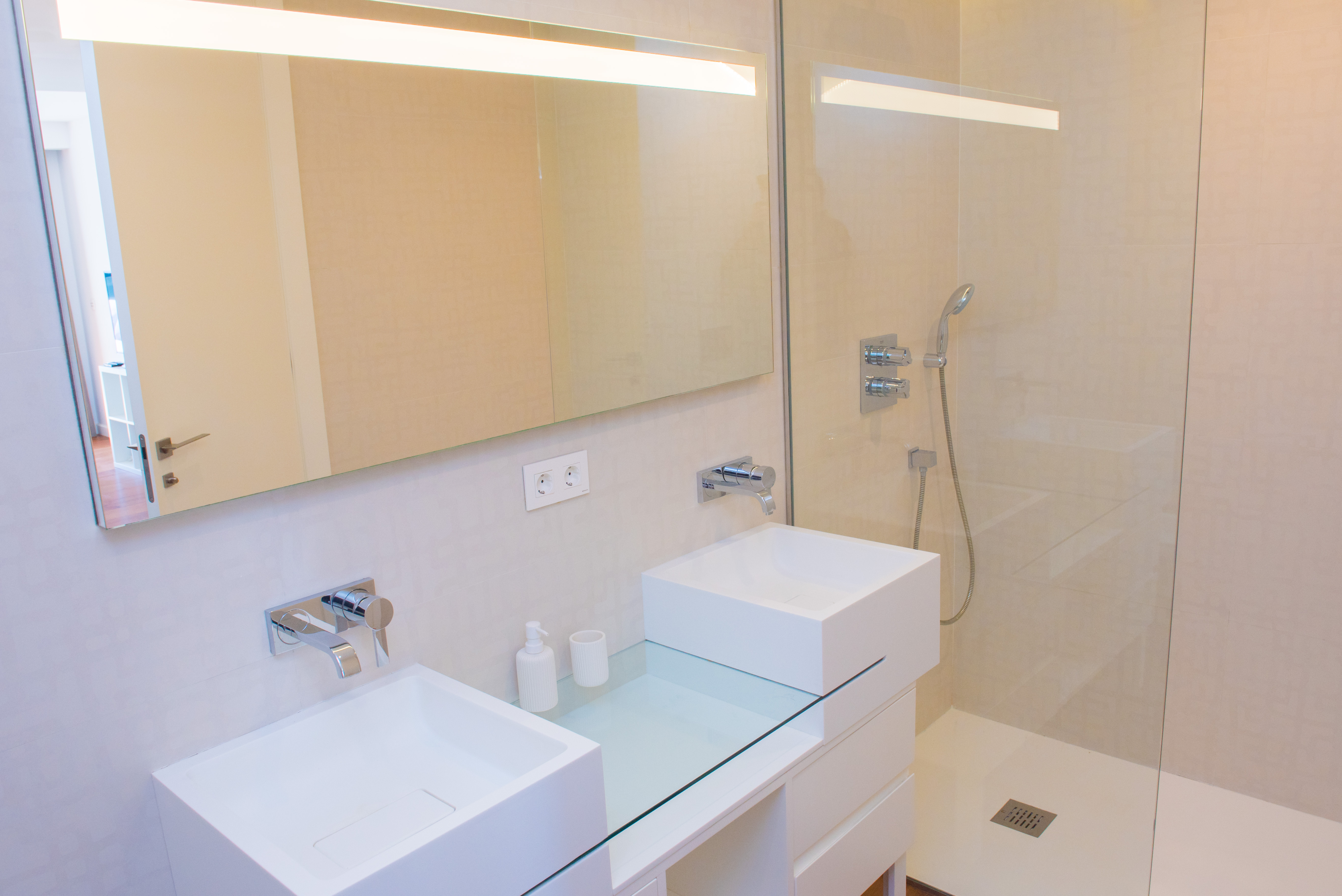 Salle de bains contemporaine avec double vasque carrée, robinetterie encastrée et douche à l'italienne avec paroi vitrée et miroir à éclairage LED.
