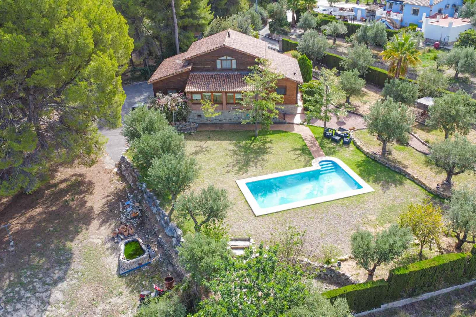 Vue aérienne de la villa en pin finlandais avec piscine privée, entourée d'un jardin méditerranéen composé d'oliviers et de pins à Orba.