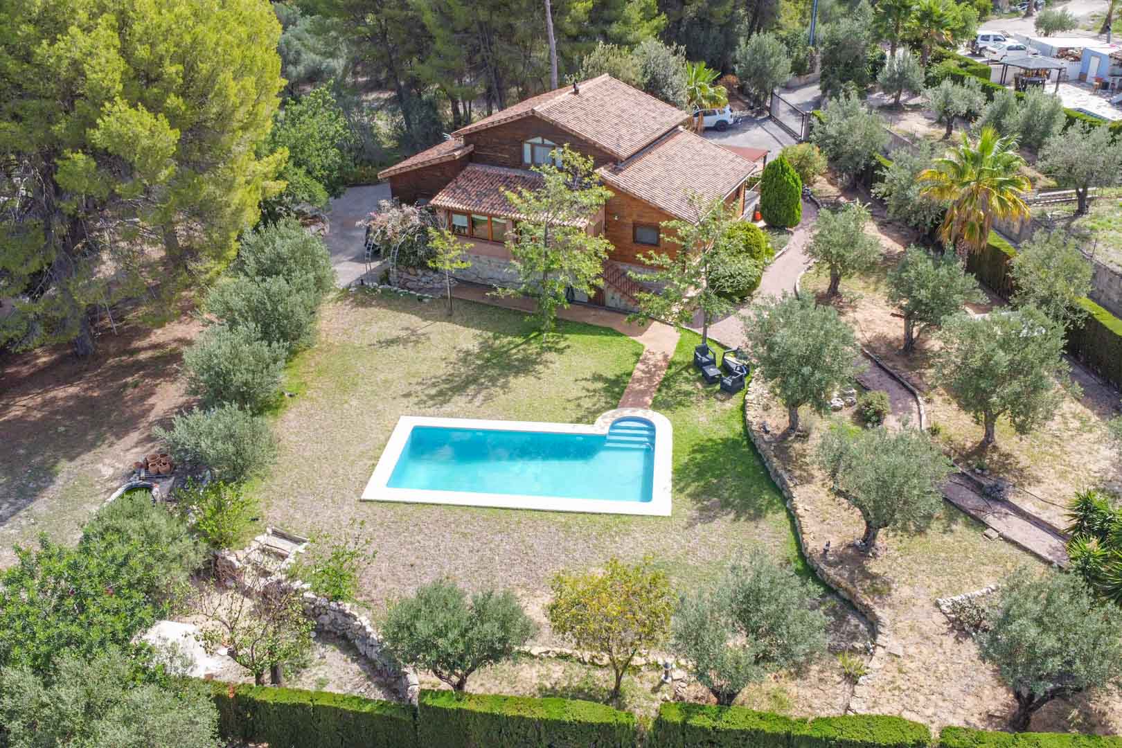 Vue aérienne de la villa en pin finlandais et pierre, mettant en valeur la piscine privée entourée d'oliviers et de jardins méditerranéens à Orba.