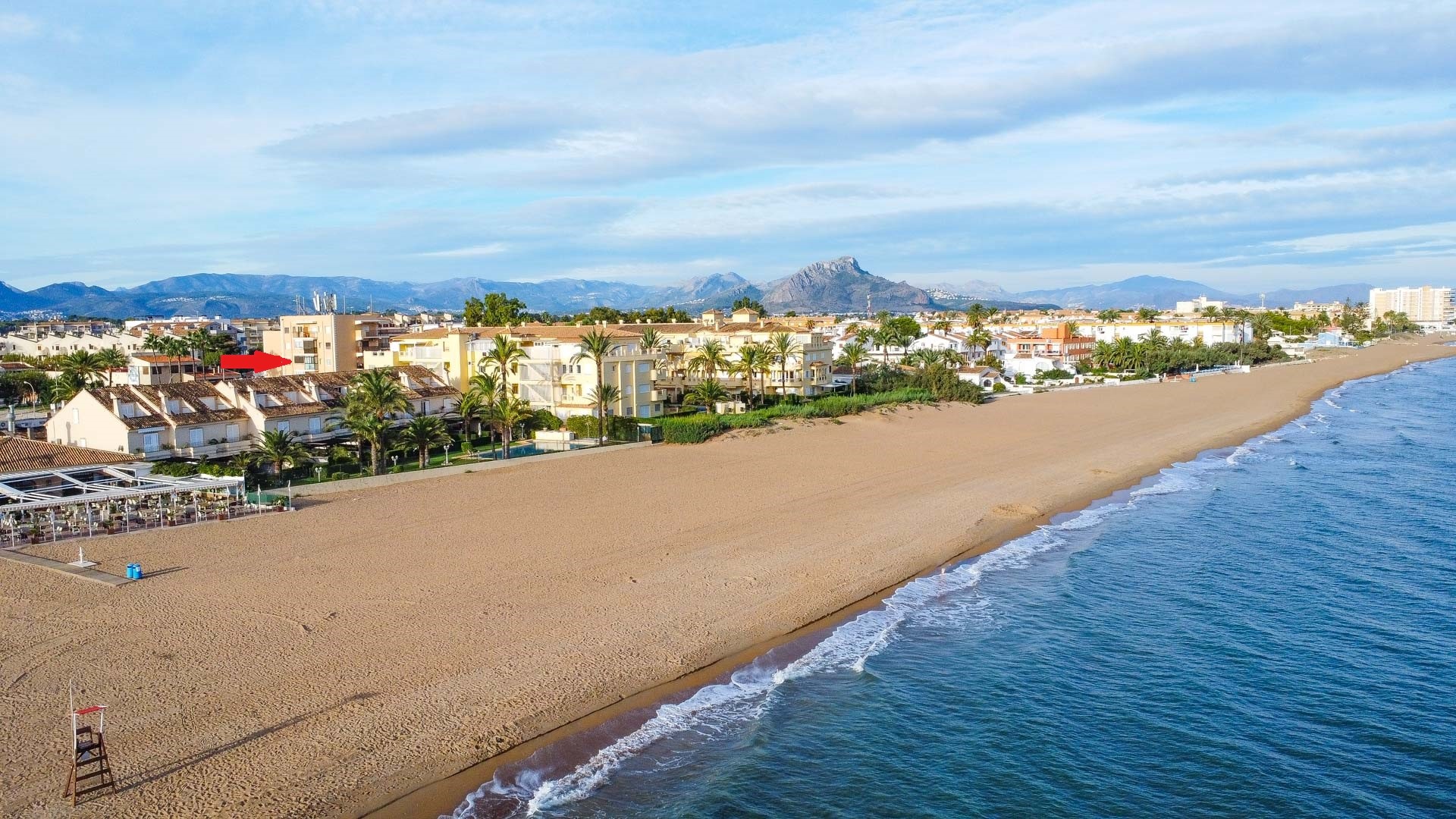 Vue aérienne de la vaste plage de sable et du littoral méditerranéen, illustrant l'emplacement de l'appartement entre mer et montagnes.