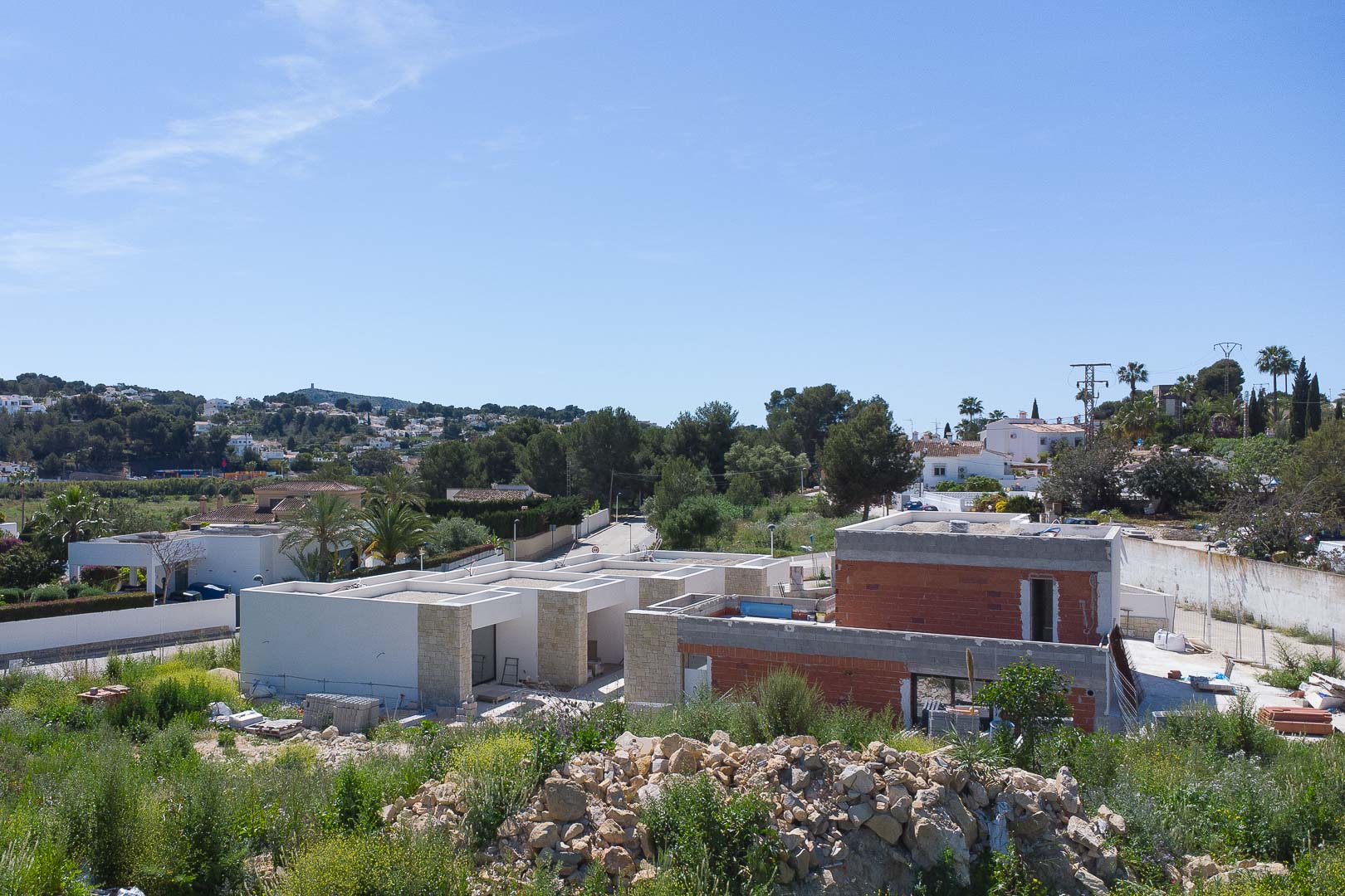Vue extérieure de la propriété en construction, mettant en valeur les murs en pierre naturelle et les lignes architecturales modernes à Moraira.