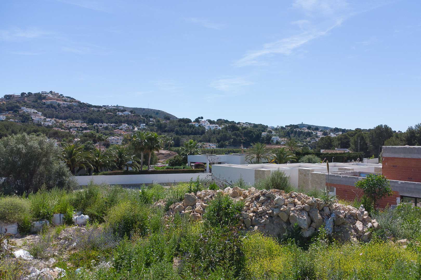 Vue panoramique depuis le terrain sur les collines de Moraira, illustrant l'environnement naturel et les villas environnantes.