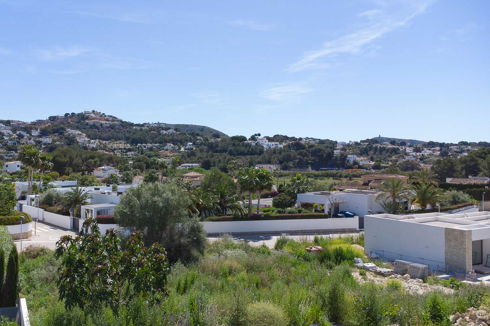 Vue panoramique sur le quartier résidentiel de Moraira, mettant en valeur les villas blanches modernes et la végétation méditerranéenne sous un ciel bleu azur.