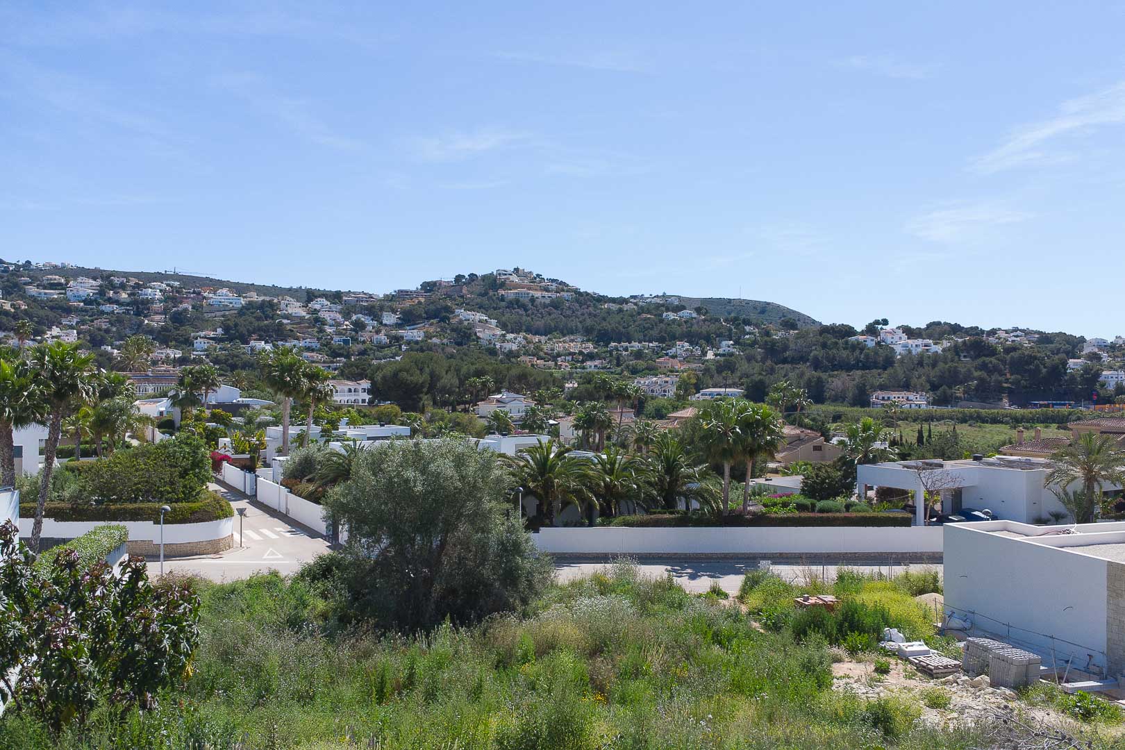 Vues panoramiques depuis la propriété sur le paysage résidentiel de Moraira, avec des collines verdoyantes et une architecture méditerranéenne.