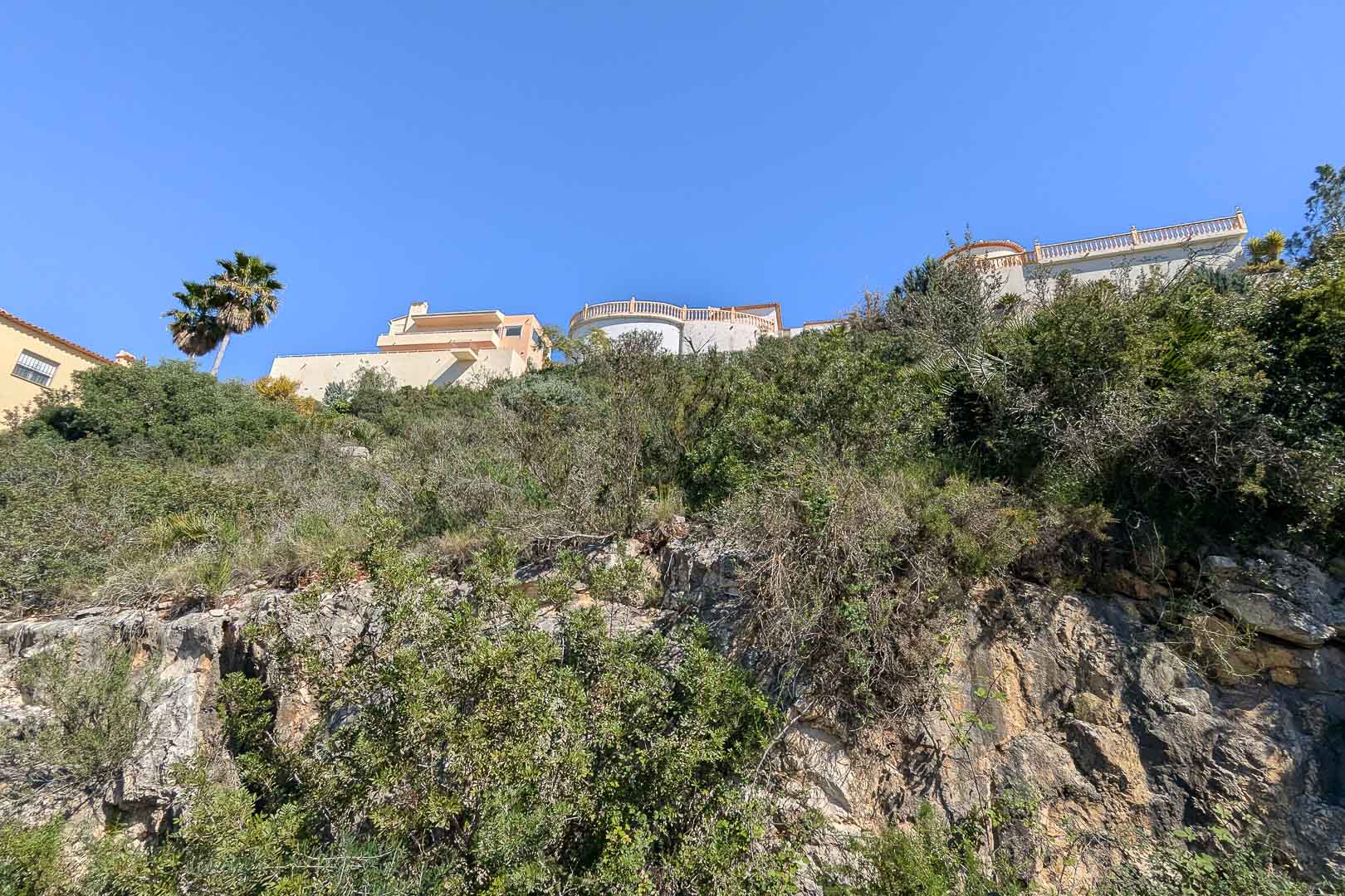 Vue de la villa en construction depuis la base rocheuse, mettant en valeur son intégration au paysage.