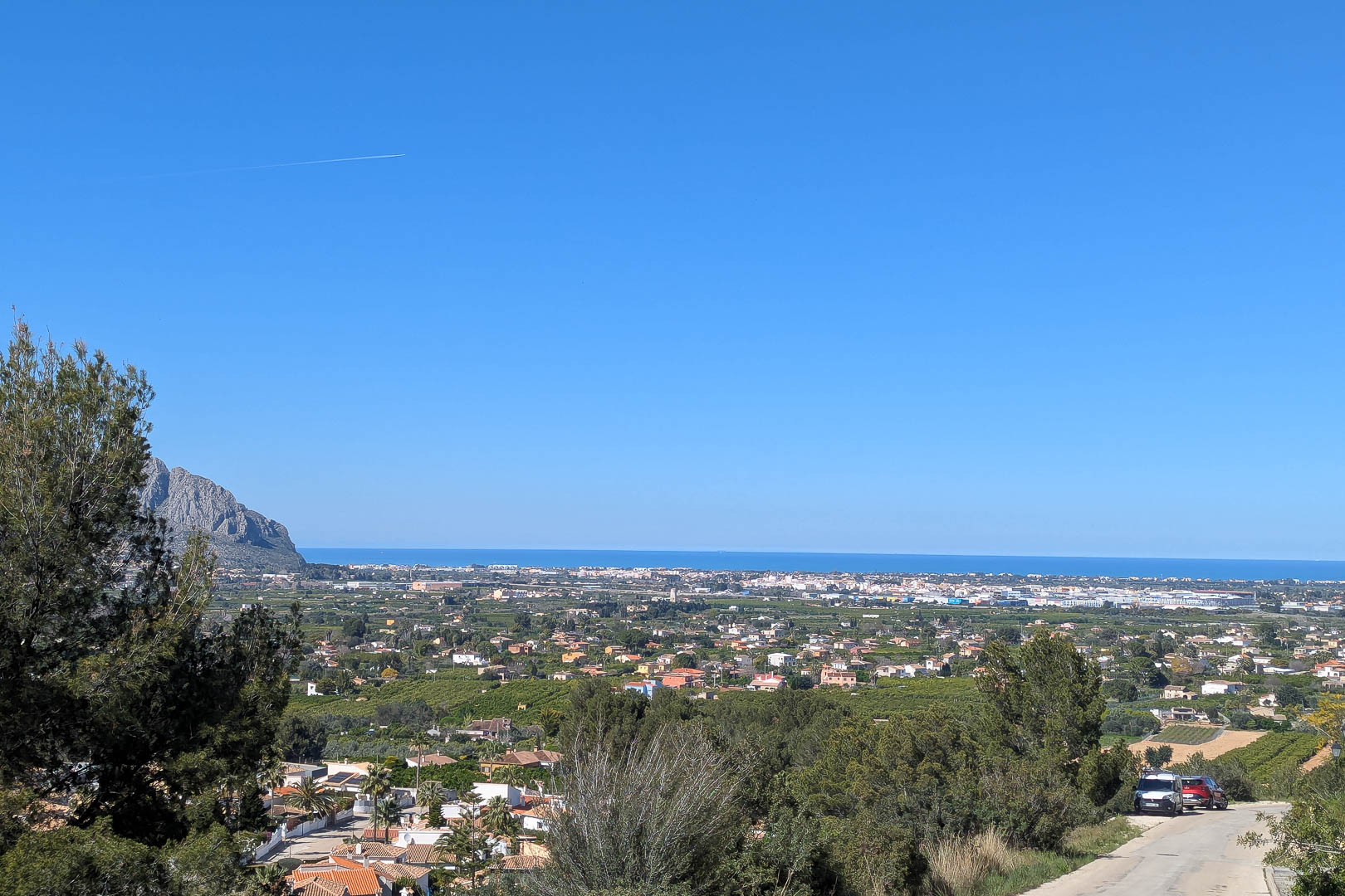 Vue panoramique de Pedreguer, avec la mer Méditerranée en arrière-plan et une végétation luxuriante au premier plan.