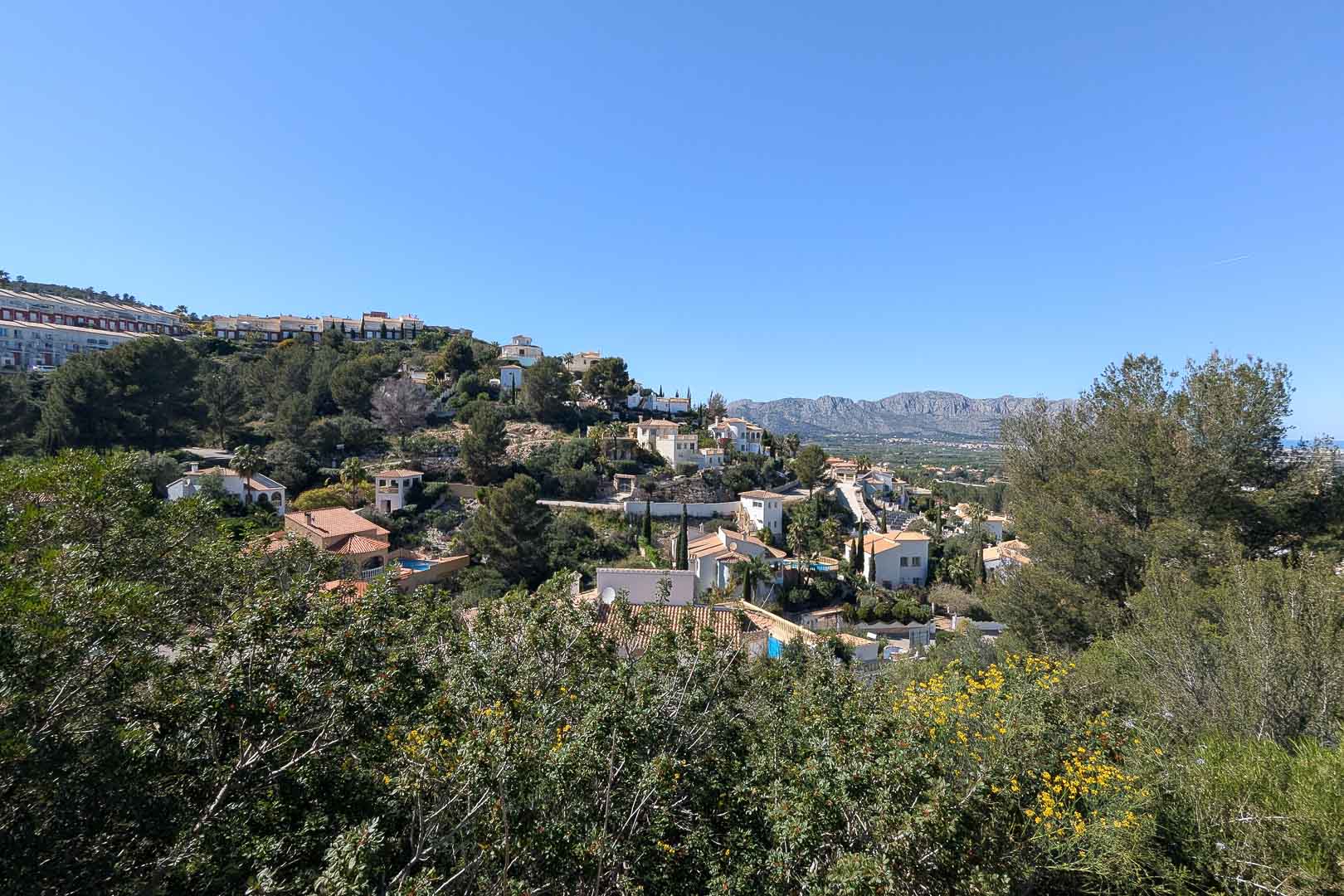 Vue panoramique du quartier résidentiel avec des maisons aux tuiles rouges et une végétation luxuriante sous un ciel bleu.