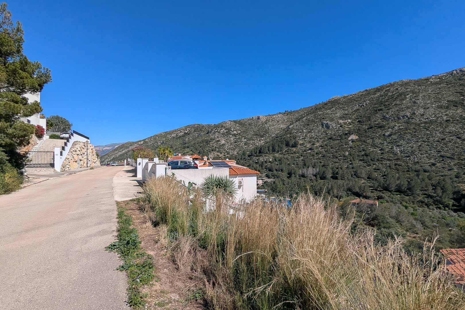 Vue extérieure de la villa depuis le chemin d'accès, montrant les panneaux solaires sur le toit et l'environnement naturel des montagnes environnantes.