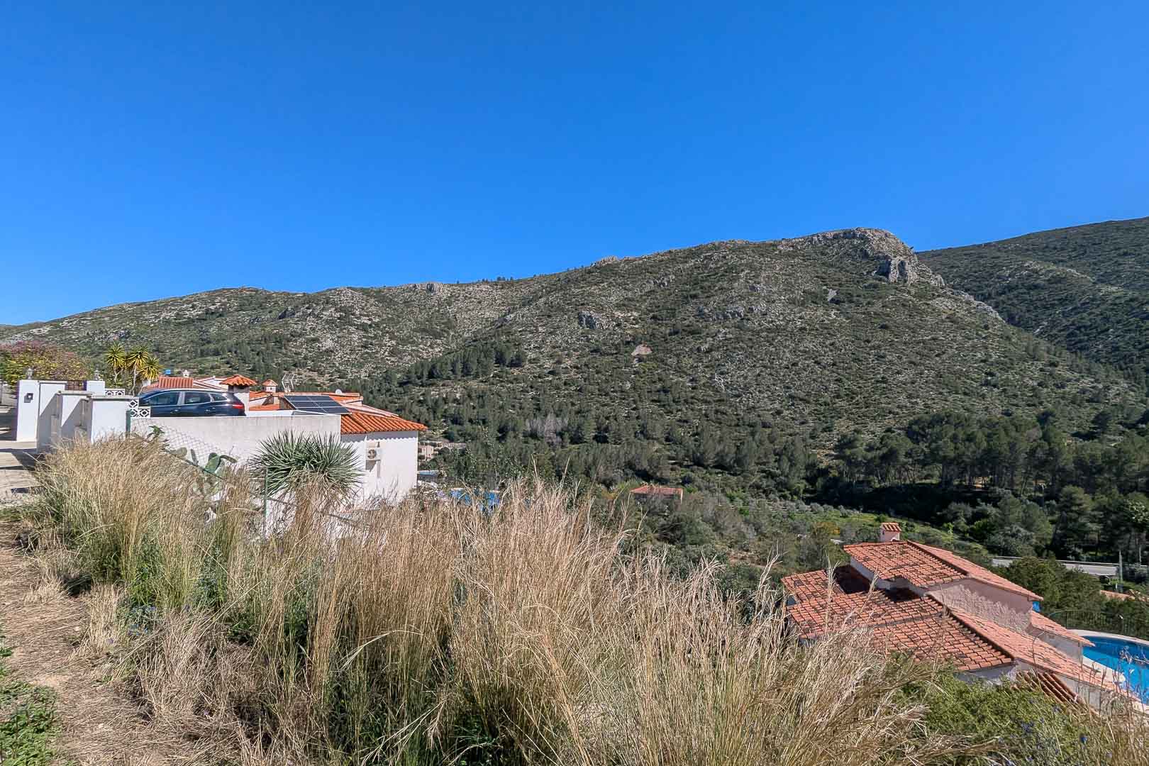 Vues panoramiques sur les montagnes et la vallée depuis le terrain, mettant en valeur le paysage naturel et les villas méditerranéennes voisines.