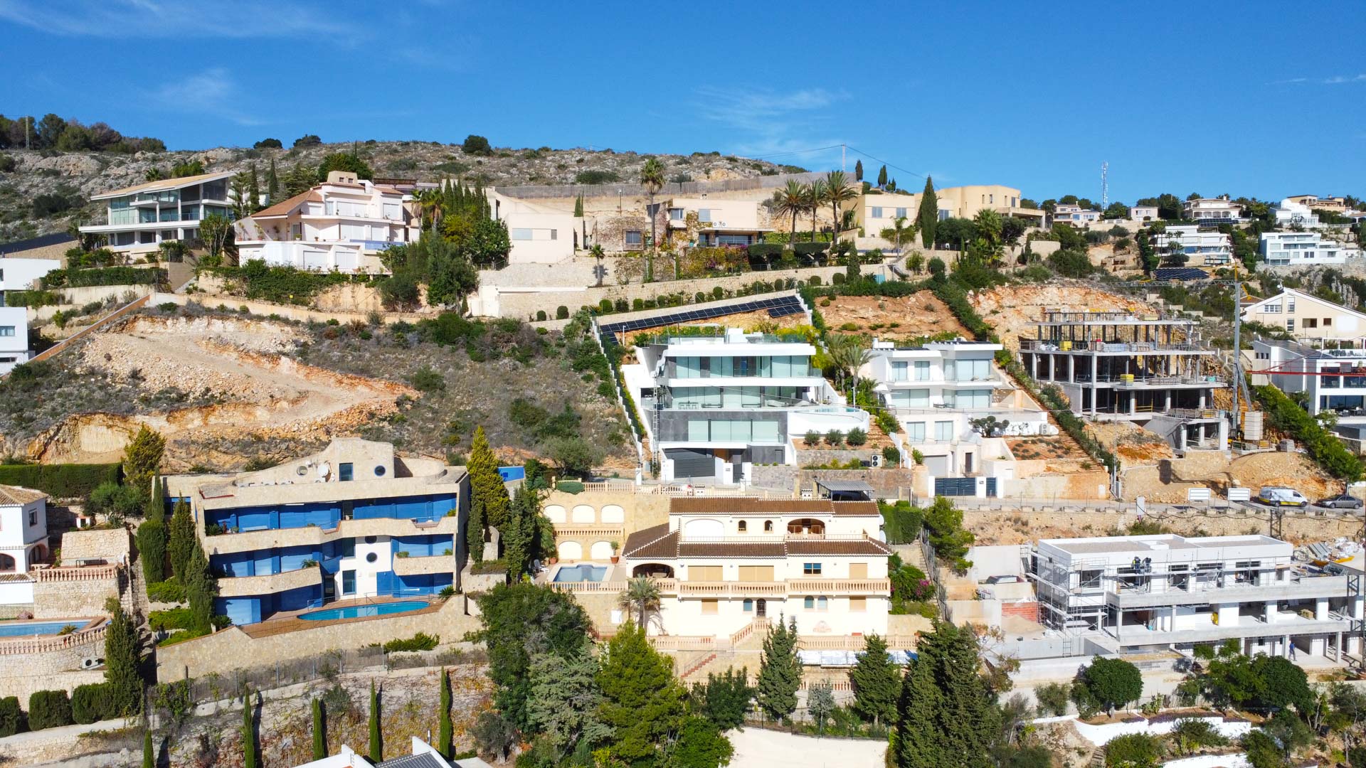Vue aérienne de la villa sur la colline de La Corona, illustrant son architecture traditionnelle sur trois niveaux avec toits en tuiles et terrasses intégrées au relief escarpé.