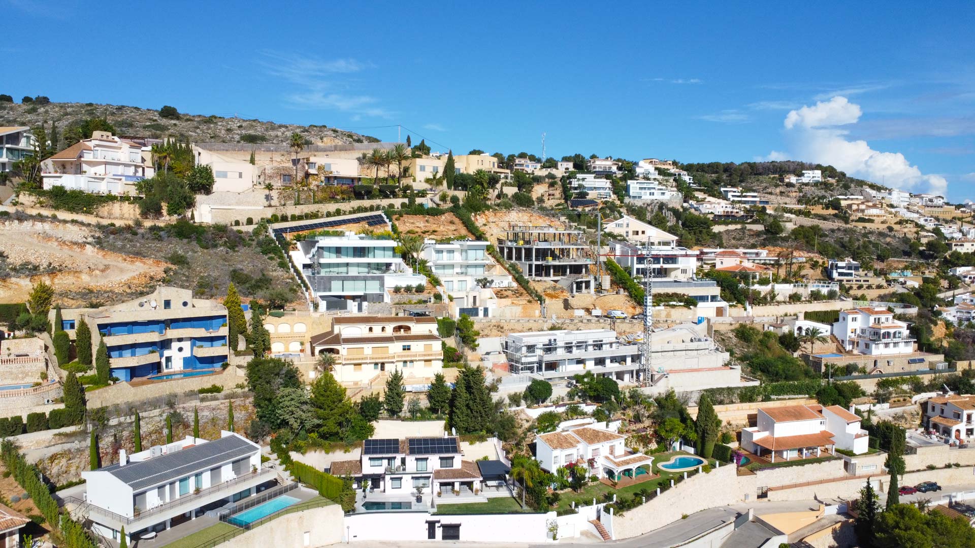 Vue aérienne du quartier résidentiel La Corona à Jávea, illustrant l'implantation en terrasses des villas sur la colline face à la mer Méditerranée.