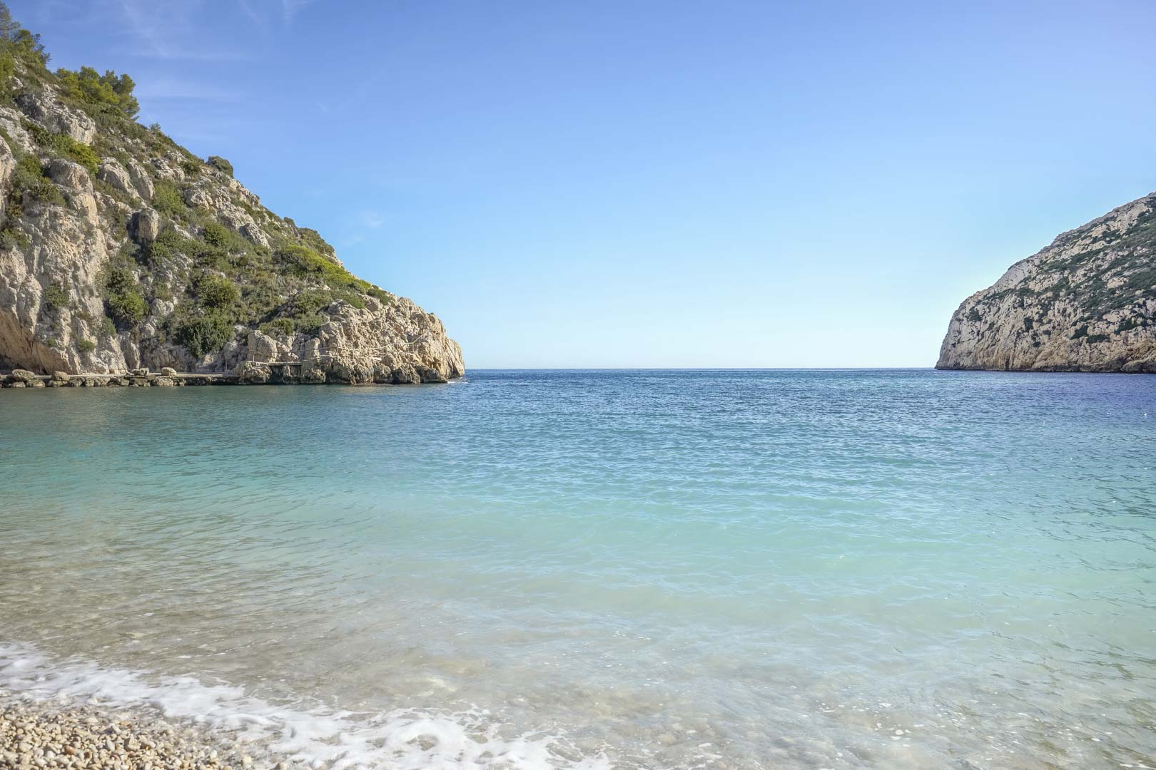 Vue d'une crique méditerranéenne aux eaux turquoise et plage de galets, entourée de falaises escarpées à proximité de la villa à Jávea.