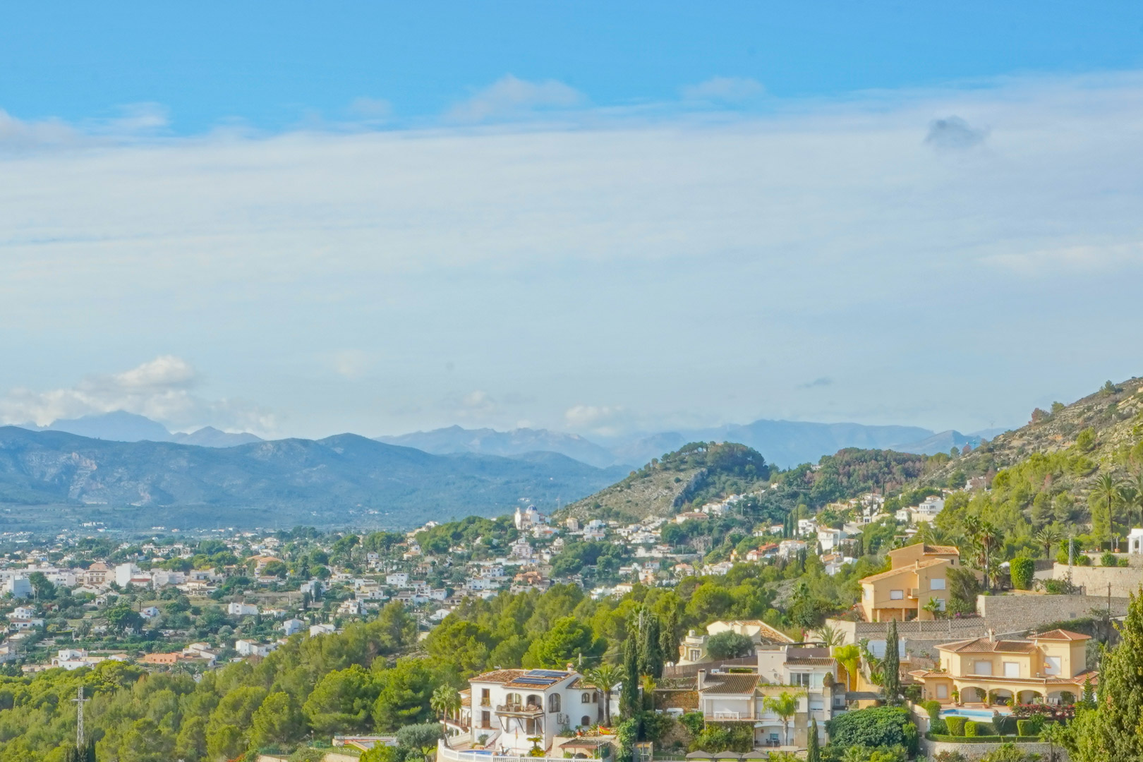 Vue panoramique depuis la propriété sur la vallée et les chaînes de montagnes environnantes, illustrant la végétation méditerranéenne et le quartier résidentiel.