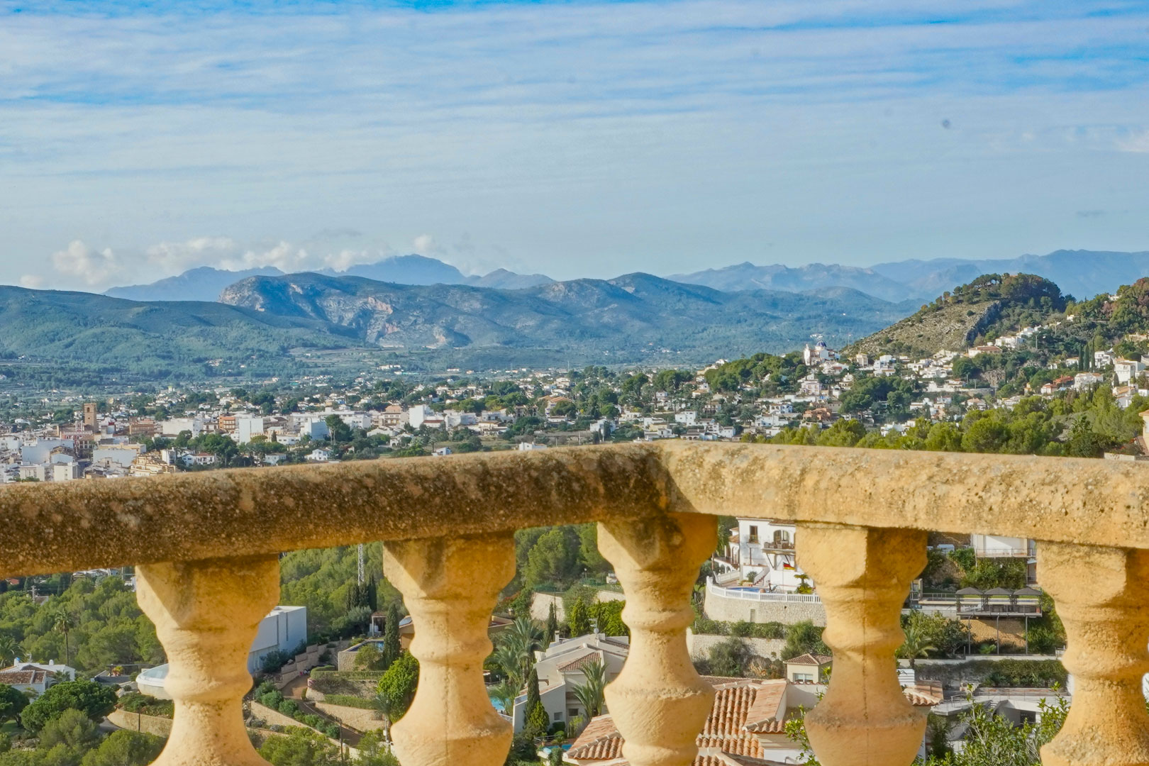 Vue panoramique depuis la terrasse avec balustrade en pierre traditionnelle, surplombant la vallée de Jávea et les chaînes de montagnes environnantes.