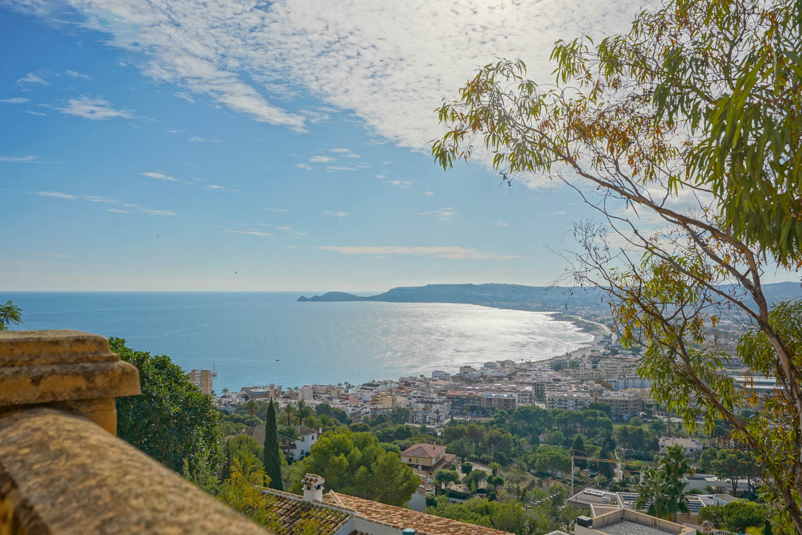 Vue panoramique depuis la terrasse sur la baie de Jávea et le Cap Negre, englobant le port et le littoral méditerranéen sous un ciel lumineux.