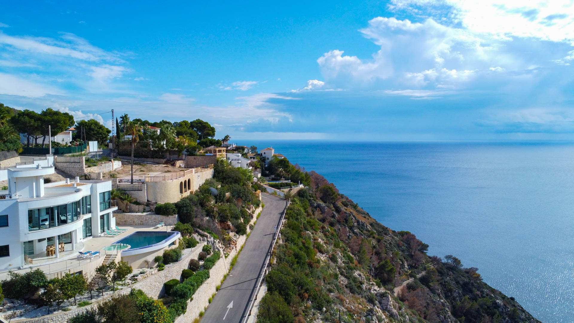 Vue aérienne du terrain surélevé offrant une vue panoramique sur la mer Méditerranée, situé à côté de villas modernes et d'une route côtière.