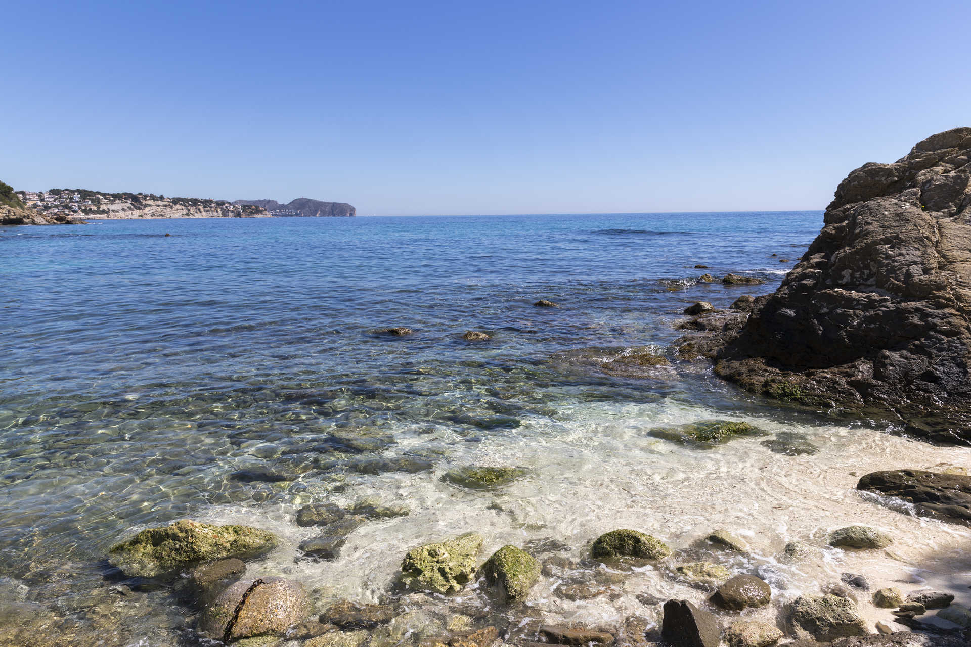 Vue de la côte méditerranéenne avec des eaux cristallines et un rivage rocheux près de la plage de La Fustera, soulignant la proximité du projet avec la mer.