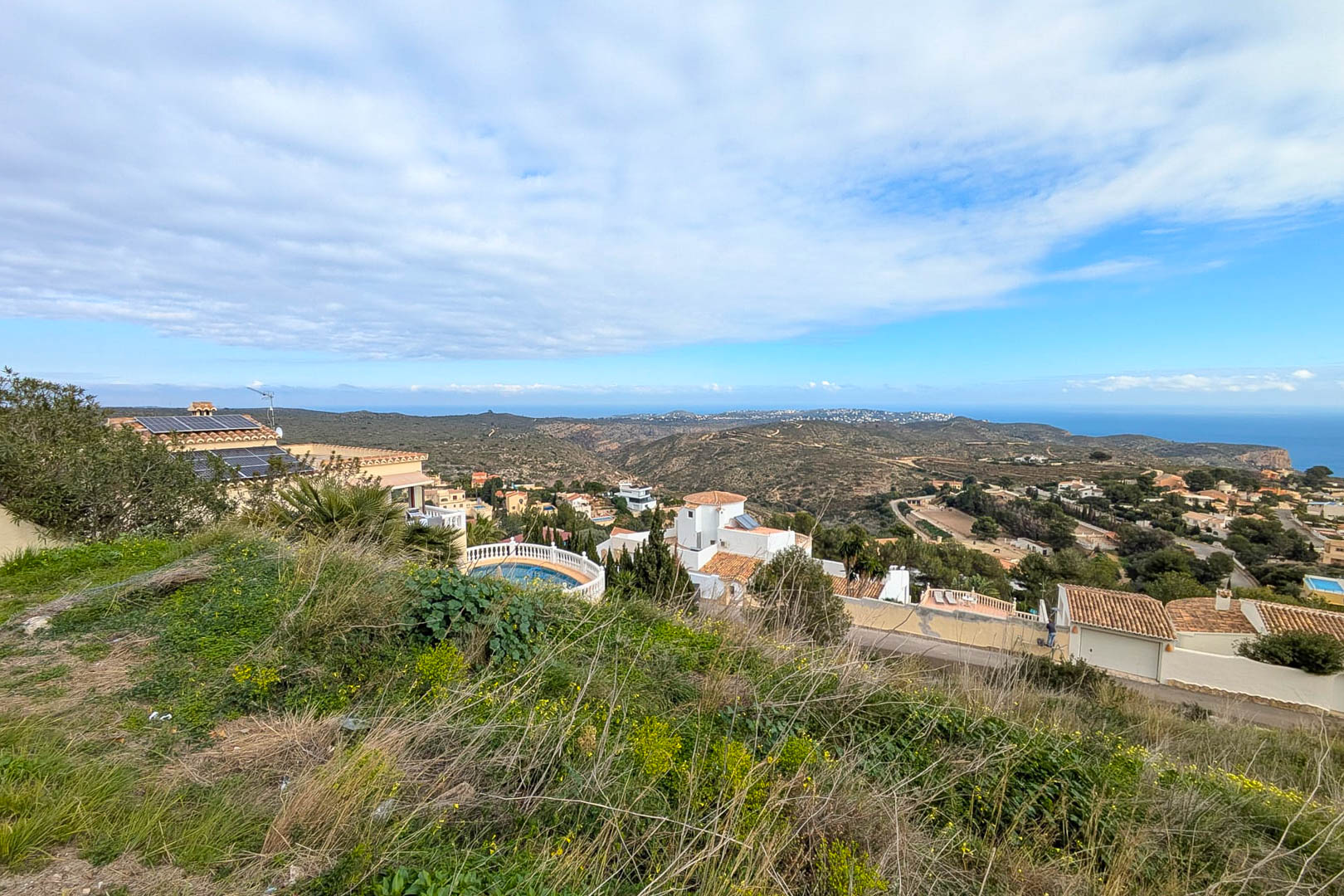 Vues panoramiques depuis le terrain surélevé sur la mer Méditerranée et la vallée, avec une végétation naturelle et des villas résidentielles environnantes.