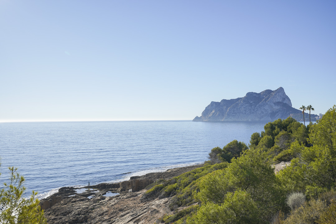 Vue panoramique sur le Peñón de Ifach et le littoral méditerranéen, mettant en valeur les rivages rocheux et la végétation de pins de Calpe.
