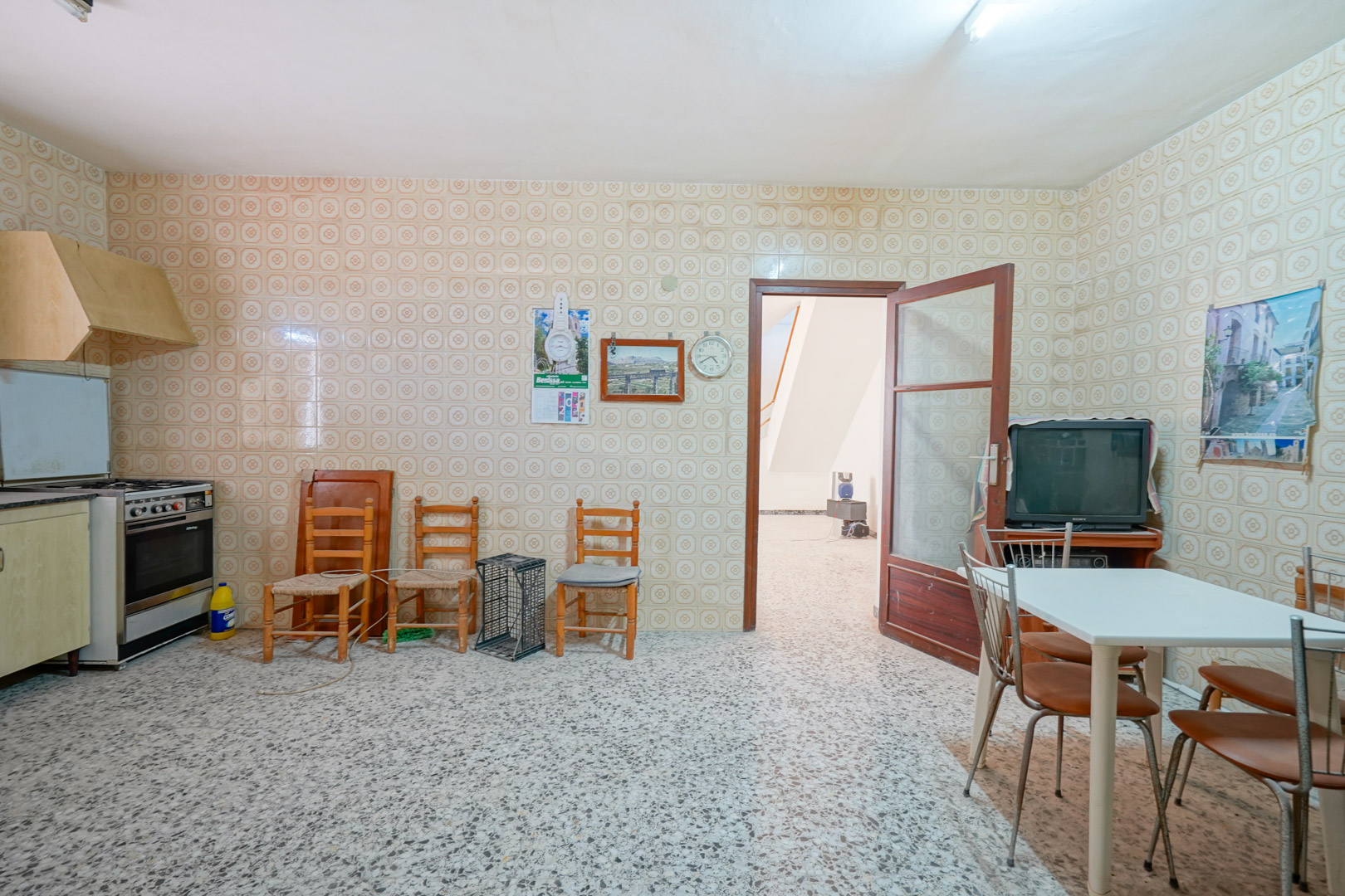 Cuisine traditionnelle avec carrelage mural d'époque, sol en terrazzo et un coin repas offrant un accès direct au couloir principal.