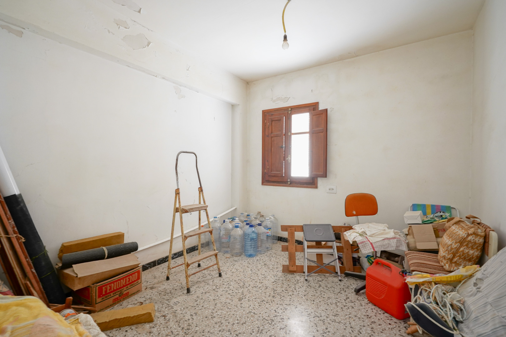 Pièce avec sol en terrazzo et fenêtre en bois munie de volets. Cet espace met en évidence le potentiel de rénovation complète et les volumes d'origine.