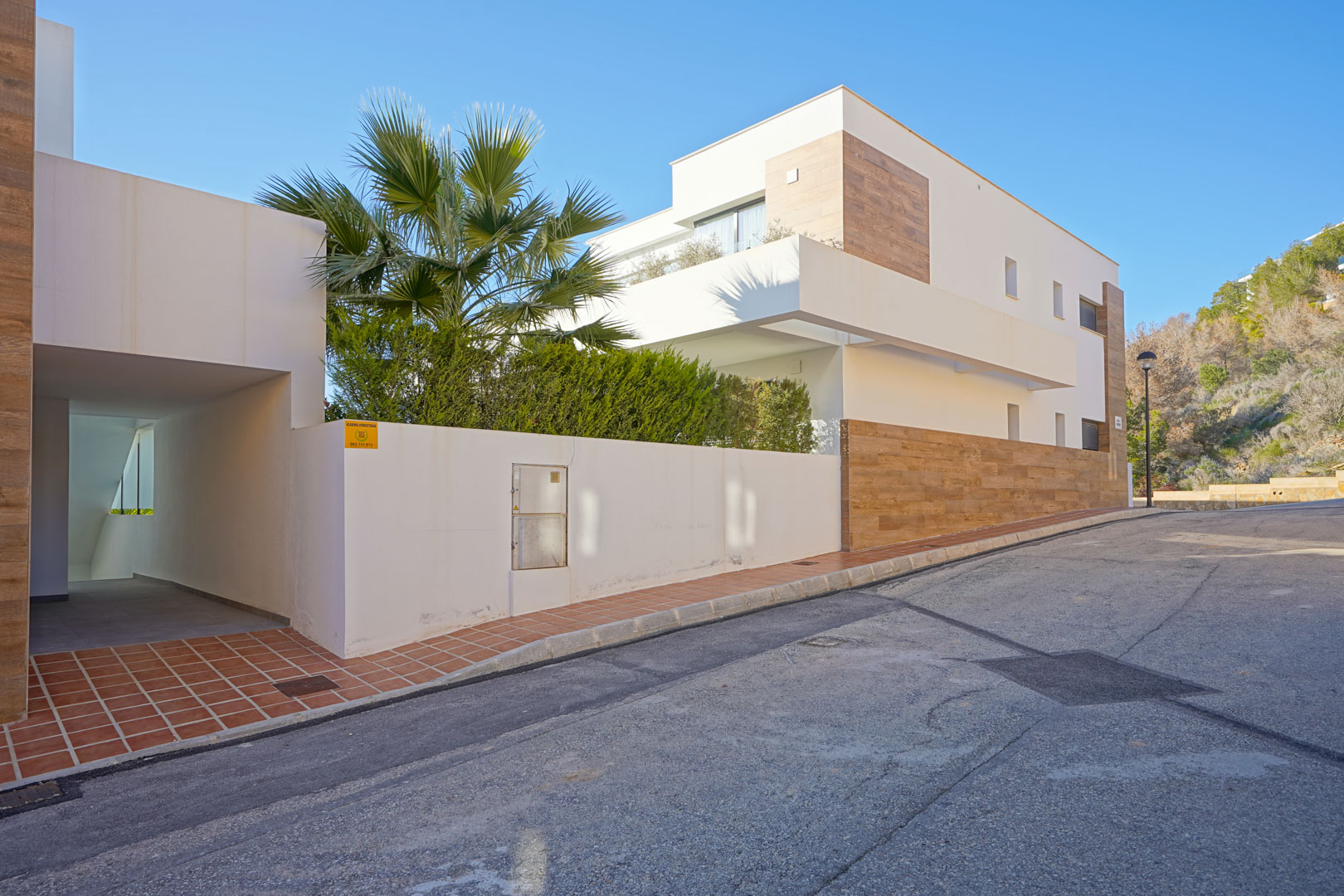 Extérieur contemporain de la résidence Monte Cala Gardens, affichant des façades blanches, des détails aspect bois et un accès piéton couvert.