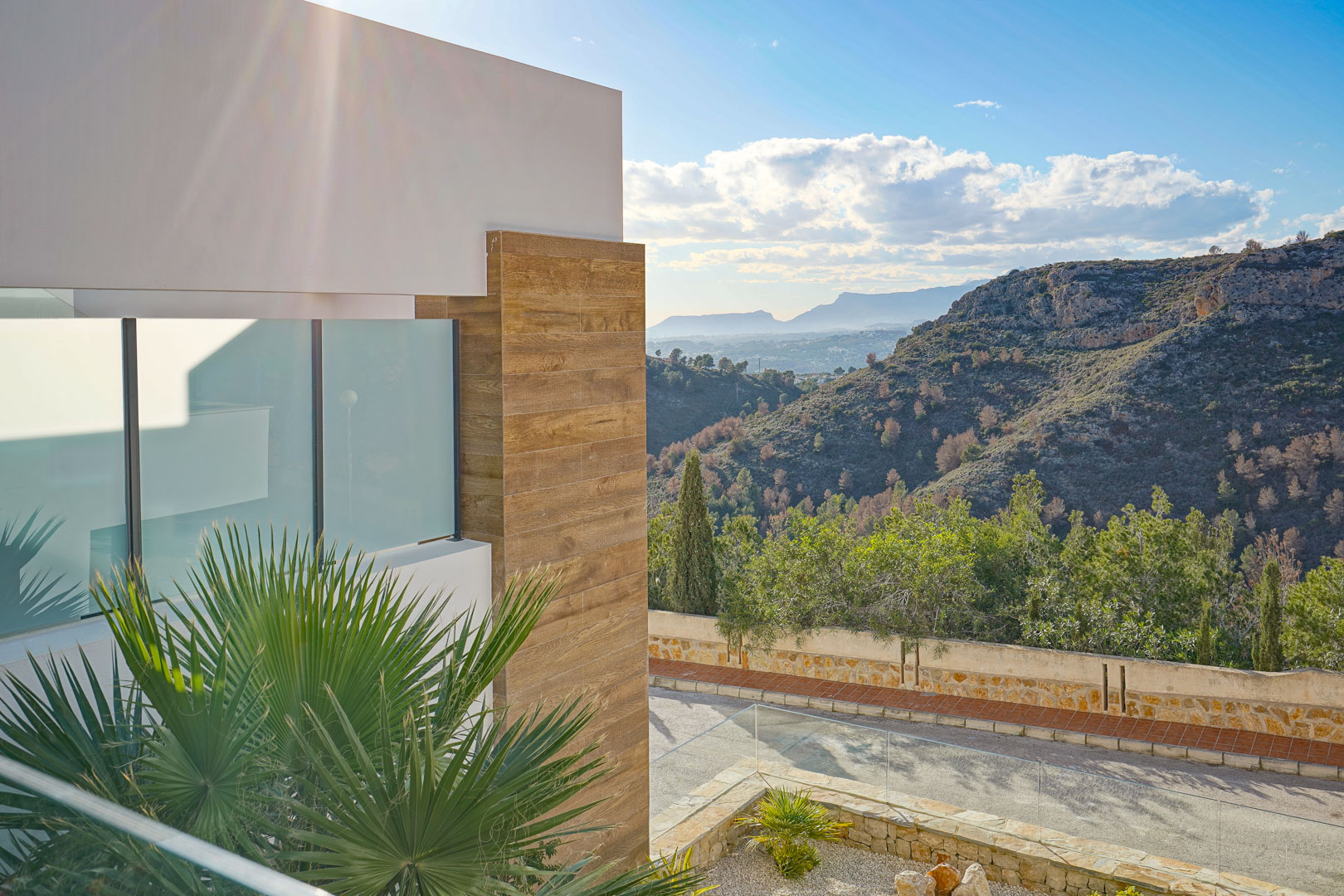 Vue extérieure depuis la terrasse avec garde-corps en verre, mettant en valeur la façade moderne aux finitions bois et la vue dégagée sur le parc naturel.