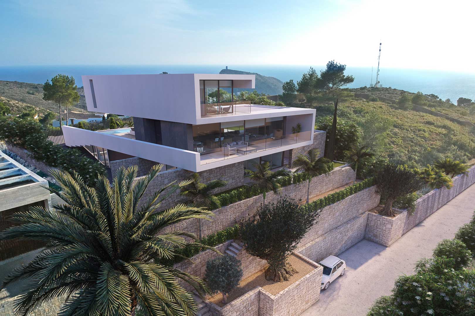 Vue extérieure de la villa moderne avec murs en pierre, terrasses vitrées et vue sur la mer.
